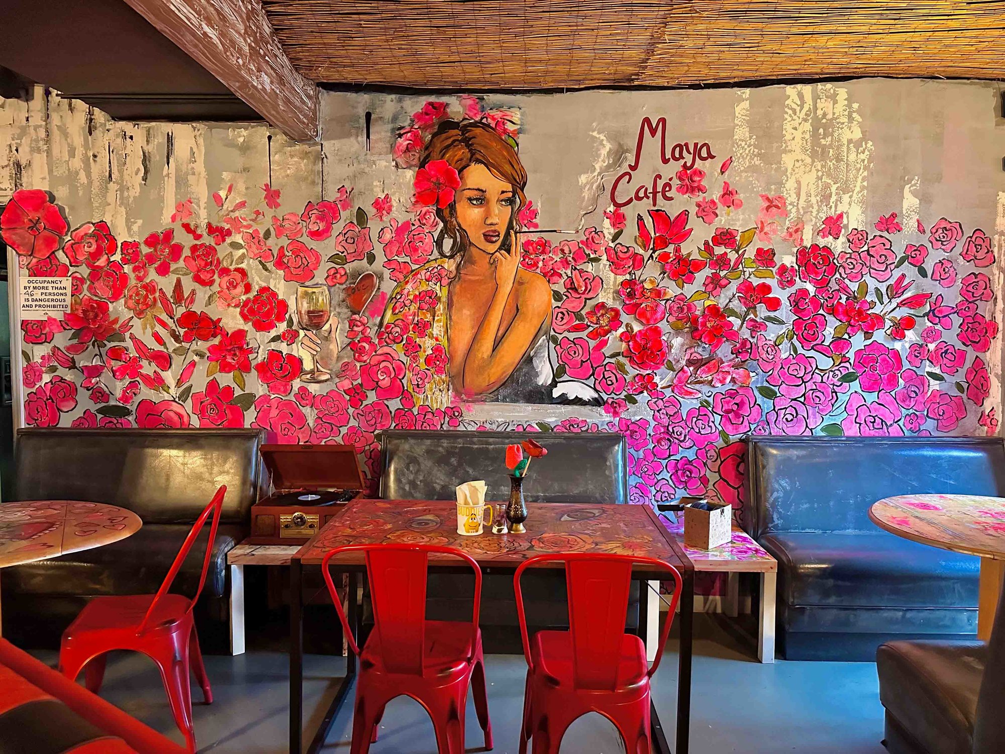 mural with pink flowers and tables and mismatched chairs